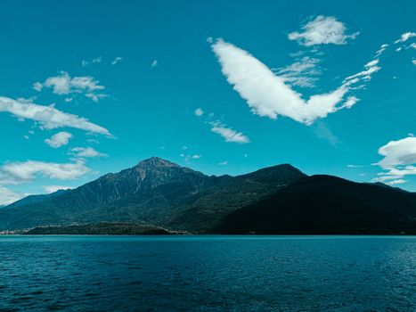 Breathtaking scenery of calm blue water of pond located against high rocky mountains under blue sky