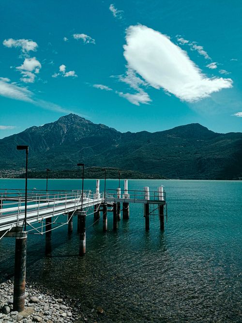 Free Scenery view of empty wooden walkway on shore of peaceful lake surrounded by rocky mountains covered with forest Stock Photo
