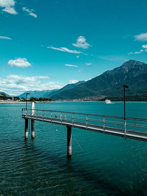 Free Magnificent scenery of narrow wooden pier above azure sea bay near rough mountains in tranquil highlands on sunny day Stock Photo