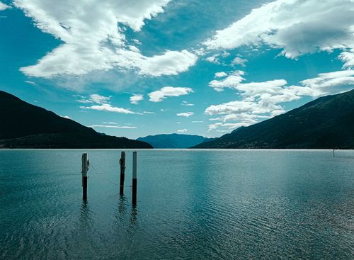Free Amazing landscape of rocky mountain range with azure sea lagoon with poles at bottom in sunny summer morning Stock Photo