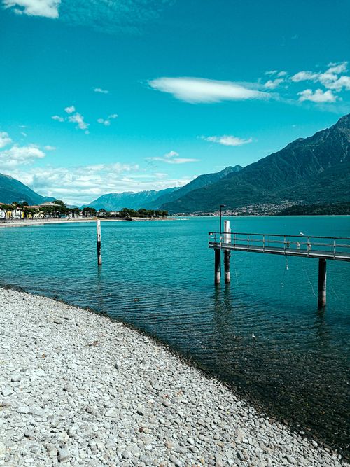 Free Idyllic scenery of remote village located on peaceful vast lakeside near majestic mountain ridge on sunny weather Stock Photo