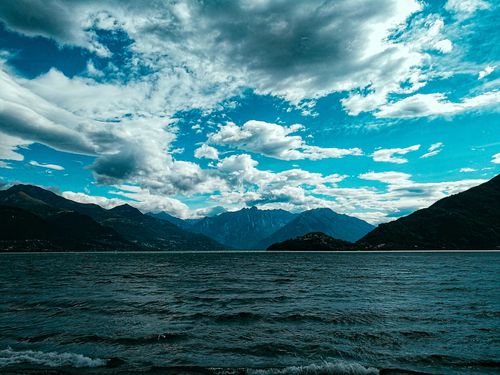 Free Magnificent view of rough mountain range  located on tranquil seashore against majestic blue sky in bright sunlight Stock Photo
