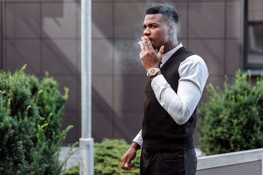 Stylish young man smoking a cigarette outside an urban building.