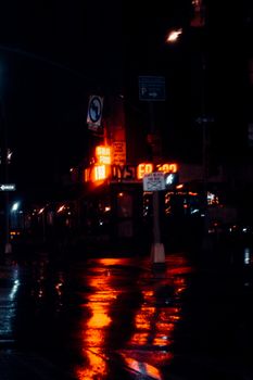 霓虹灯映在夜晚潮湿的人行道上，为充满活力的城市街道增添了戏剧性的色彩