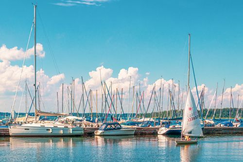 Free A serene view of sailboats at a marina under a bright blue sky, perfect for leisure activities. Stock Photo