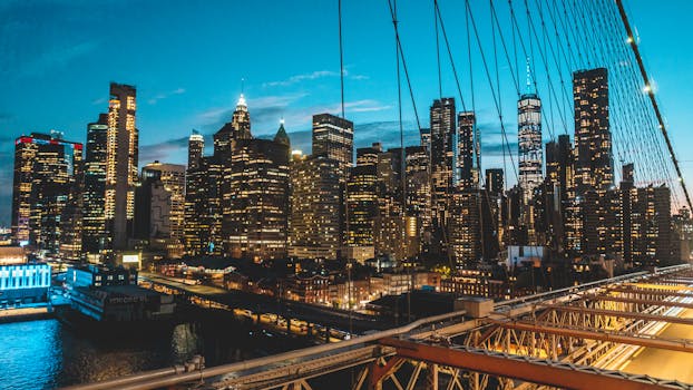 Panoramic view of New York City skyline at twilight from Brooklyn Bridge, showcasing modern skyscrapers.