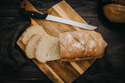 Slices of Bread and Knife on Wooden Chopping Board