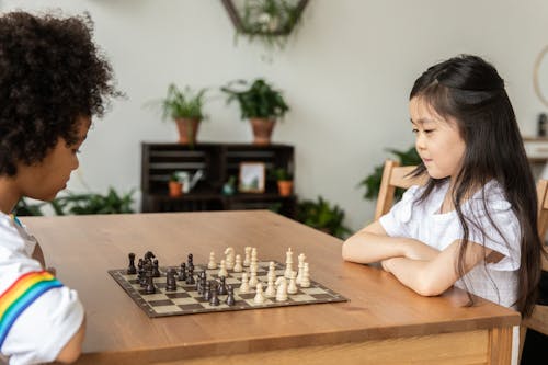 Diverse girls playing chess in bright room