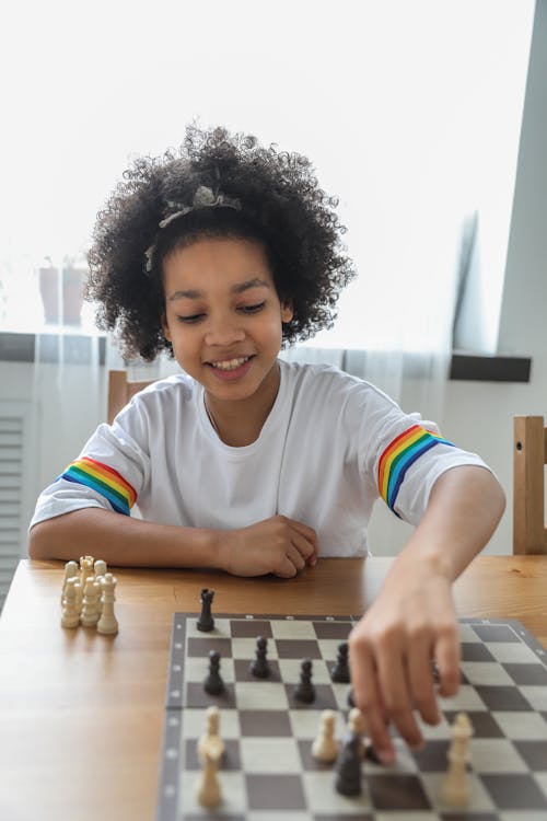 Happy black girl moving figurines on chess board