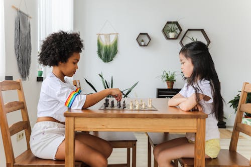 Free Multiethnic thoughtful girls playing chess in modern room Stock Photo