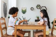 Multiethnic thoughtful girls playing chess in modern room