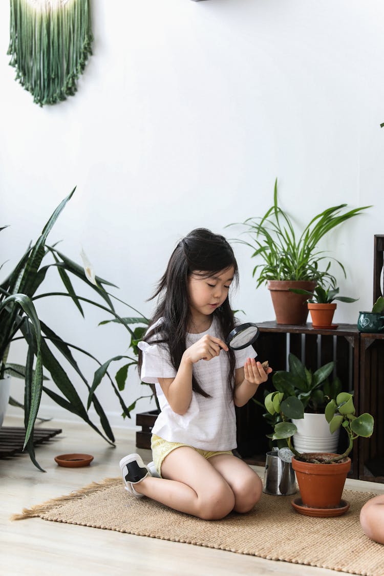 Cute Asian Girl Investigating Leaves Of Potted Plants