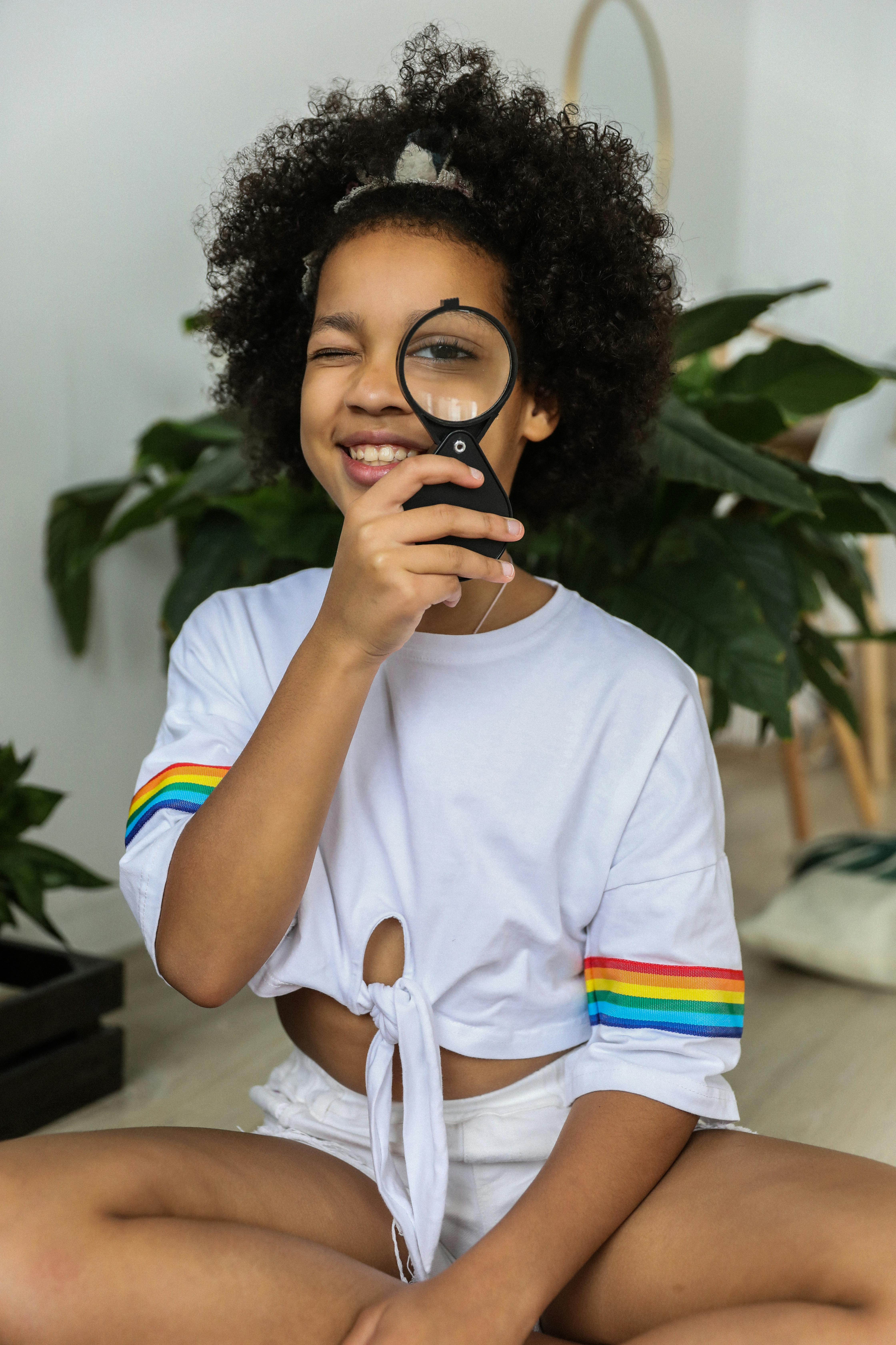 black girl smiling and looking through magnifier