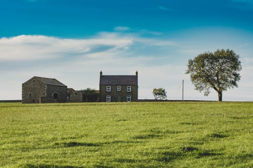 Farmhouse on Green Grass Field Under the Blue Sky