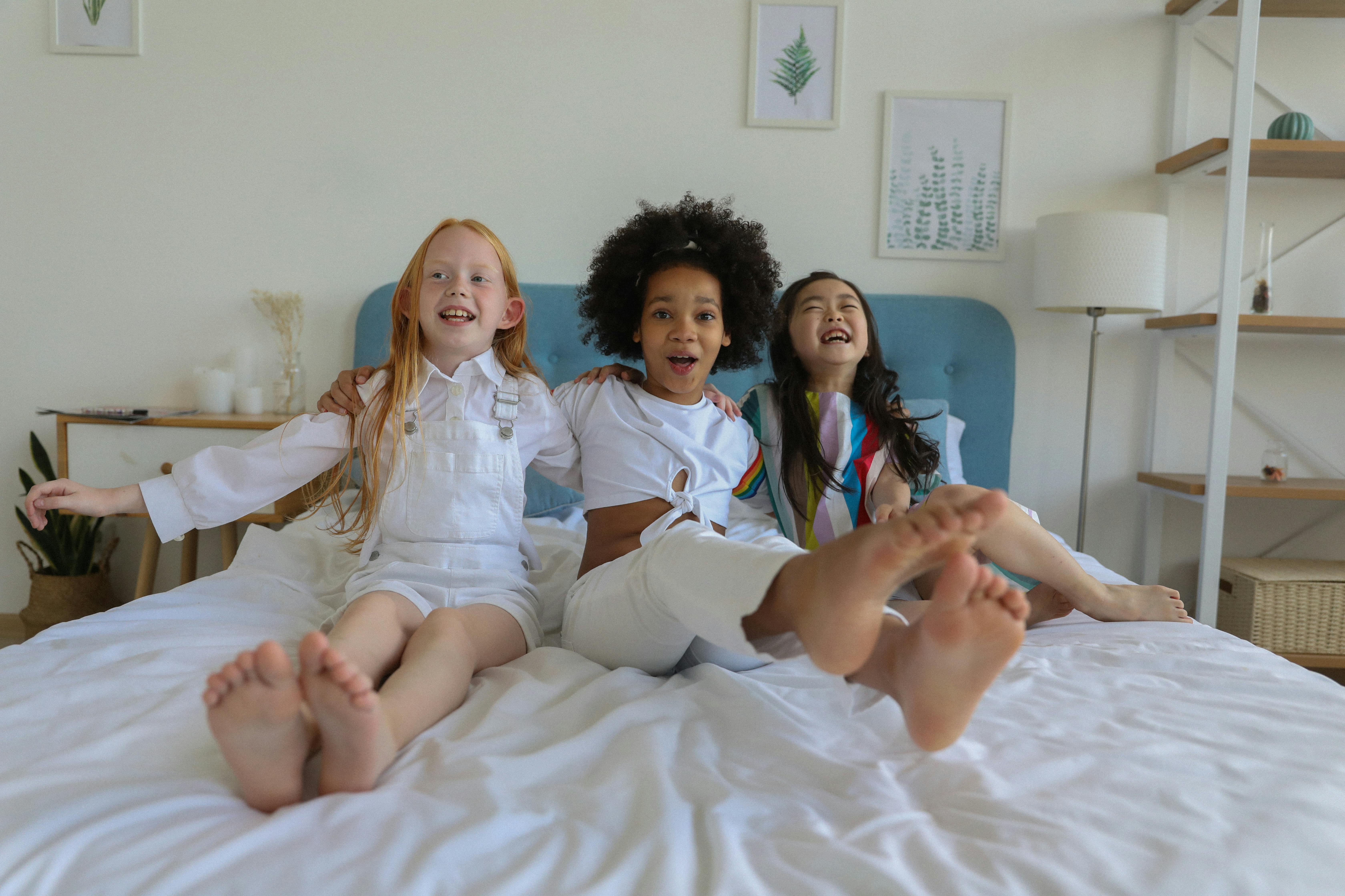 cute funny cheerful multiracial girls resting and laughing on bed