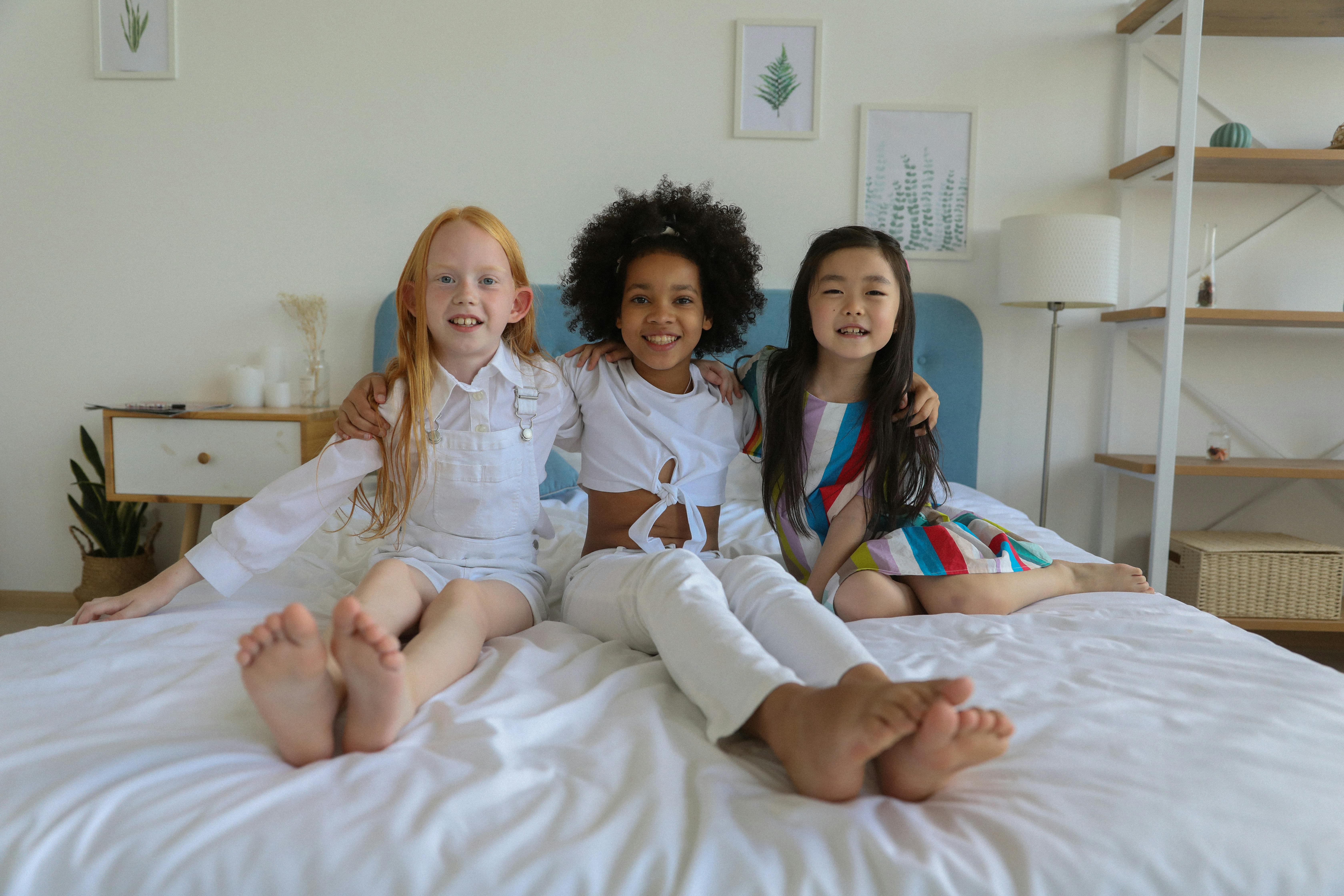 cheerful positive multiethnic girls embracing on bed