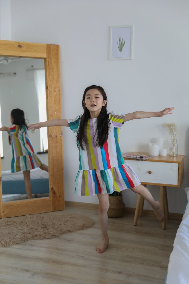 Cute Asian Girl In Bright Dress Balancing On Leg