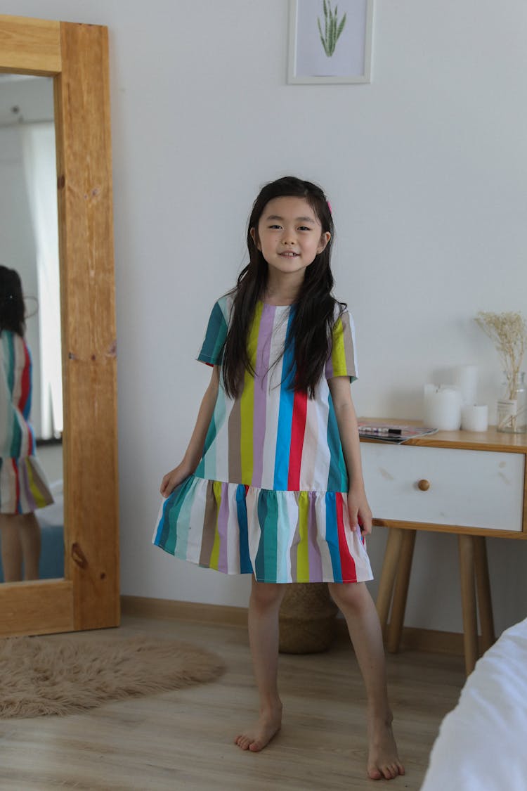 Happy Asian Girl In Colorful Dress Dancing In Room