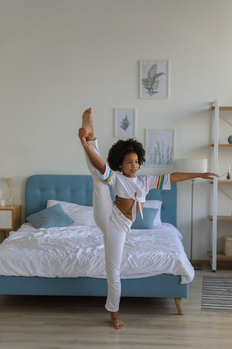 Smart Black Girl Demonstrating Splits In Bedroom