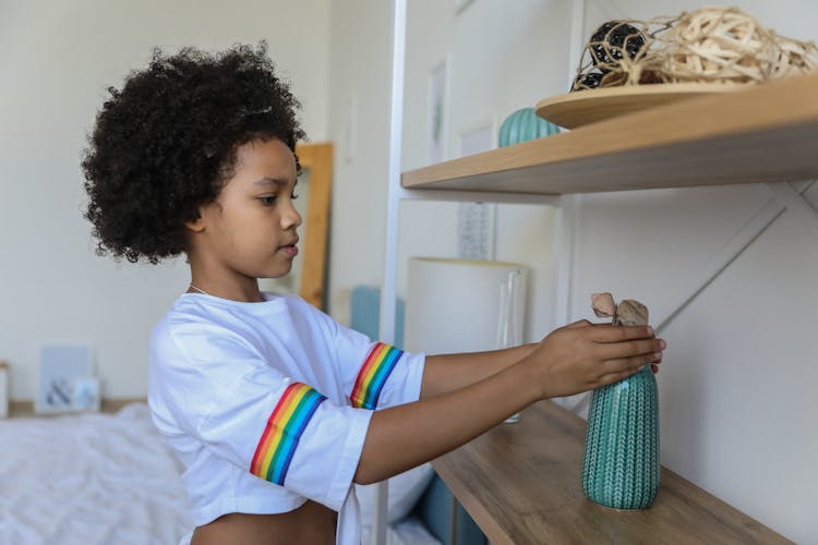 Cute Girl Organizing Shelf In Bedroom