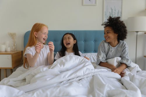 Laughing girls under blanket in bed