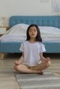 一位年轻女孩在室内的垫子上安静冥想，姿态体现了平静与正念