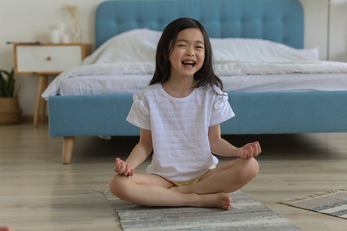 Free Happy Asian girl laughing while resting in room with legs crossed Stock Photo