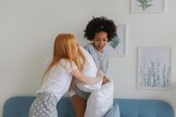 两个年轻女孩在舒适的客厅里玩枕头大战