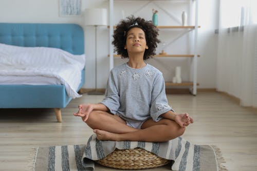 Black girl meditating in room with eyes closed