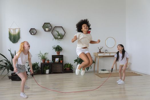 Black girl jumping over rope while playing with friends