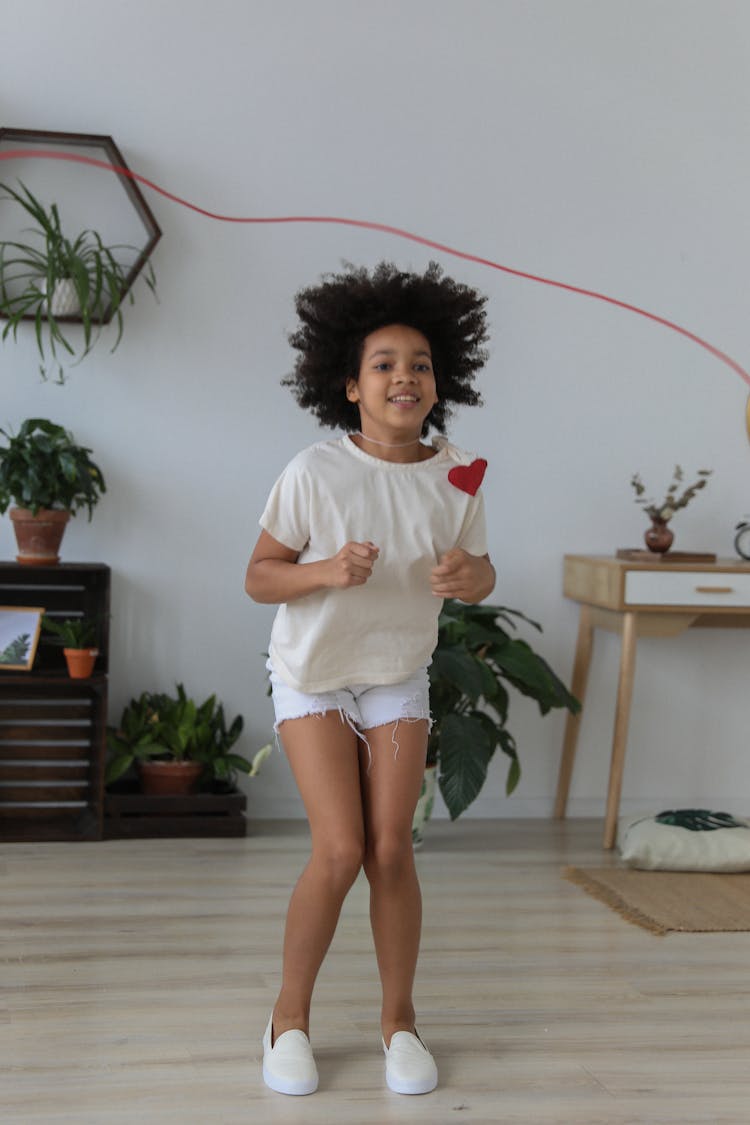 Happy Black Girl Jumping Over Rope In Bright Room