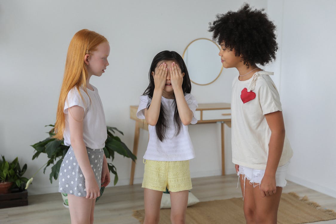 Free Cheerful multiethnic children in casual clothes playing hide and seek while spending weekends together Stock Photo