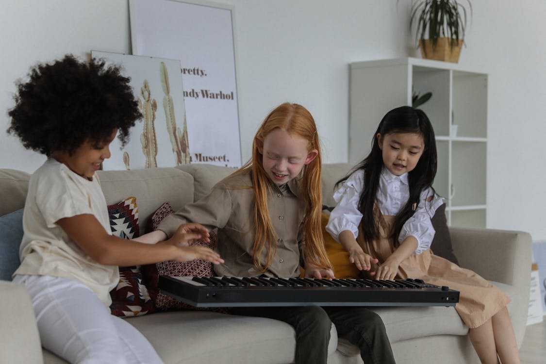 Happy multiracial little girls playing synthesizer