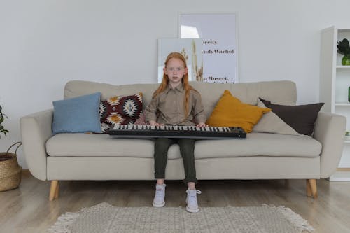 Stilvolles Kleines Mädchen Mit Synthesizer Auf Sofa