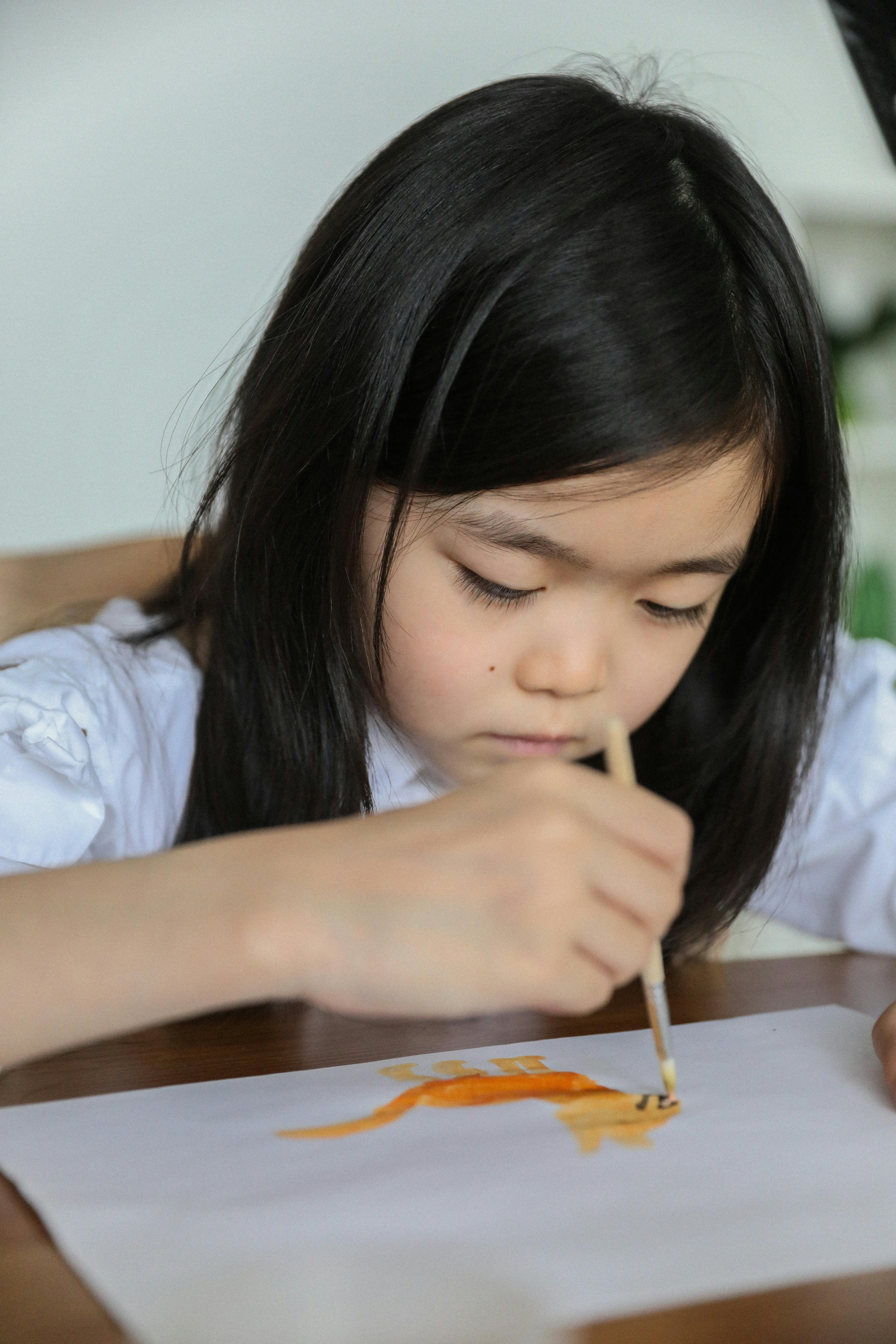 serious asian kid painting with aquarelle in art studio