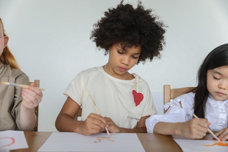 Focused Diverse Little Girls Painting With Brushes In Art Studio