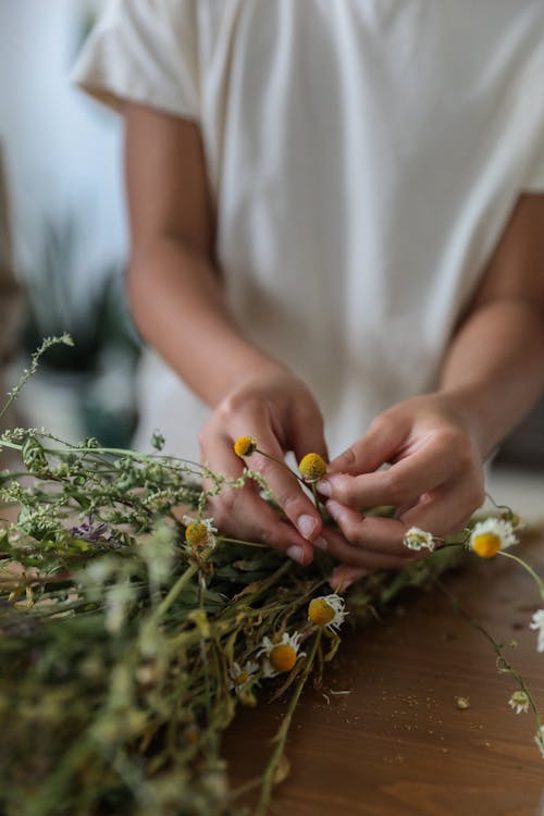 Faceless lady making delicate bouquet of tender wildflowers