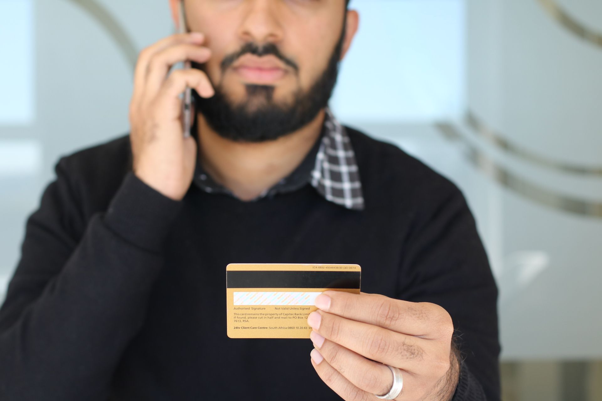 Close-up of a man holding a credit card while speaking on the phone in Johannesburg office.
