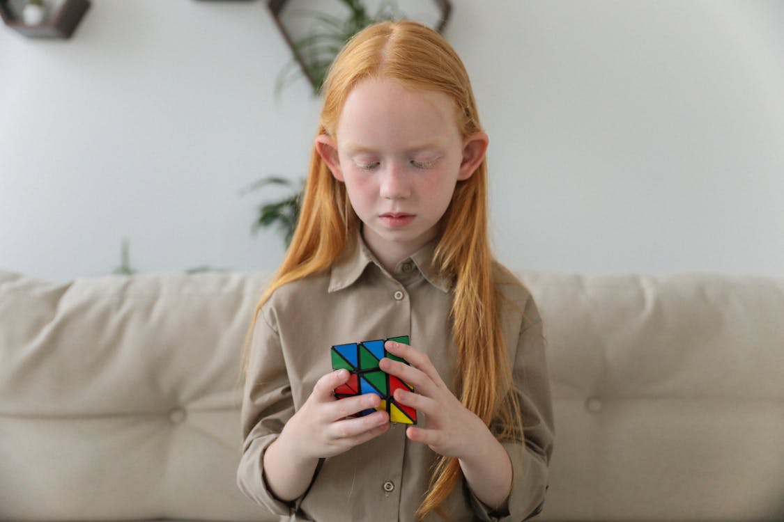 Free Cute girl thinking over bright puzzle cube Stock Photo