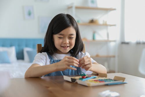 Cute happy Asian girl sculpting from plasticine