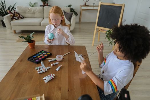 Cute diverse girls embroidering and painting