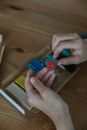 From above of crop anonymous kid creating small colorful pieces from plasticine at table