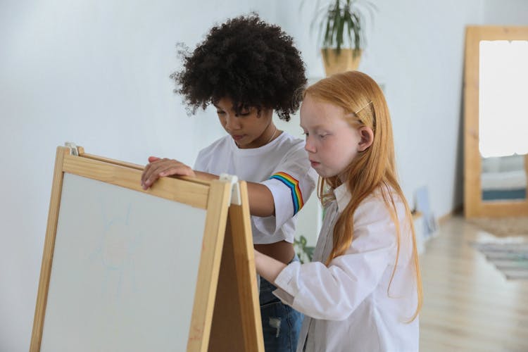 Focused Diverse Children Painting On Easel Chalkboard