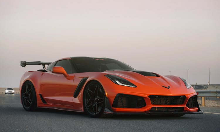 An Orange Sports Car Moving On An Asphalt Road