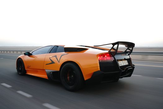 Dynamic shot of an orange Lamborghini Murcielago speeding on a highway, showcasing luxury and performance.