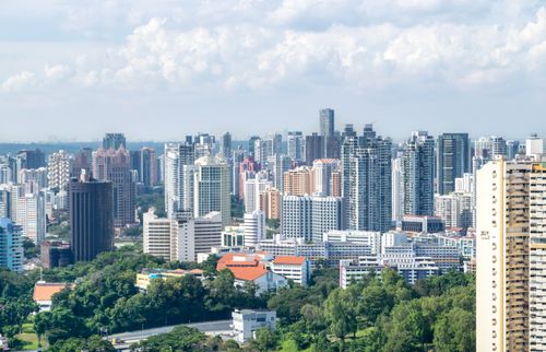 Free Aerial view of Singapore's modern skyline with lush greenery and high-rise buildings under a bright sky. Stock Photo