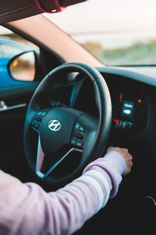 Crop unrecognizable person starting engine in contemporary auto near steering wheel in daylight