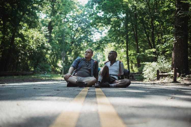 Thoughtful Friends Sitting And Resting On Road