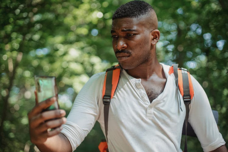 Serious Black Man Using Smartphone In Park