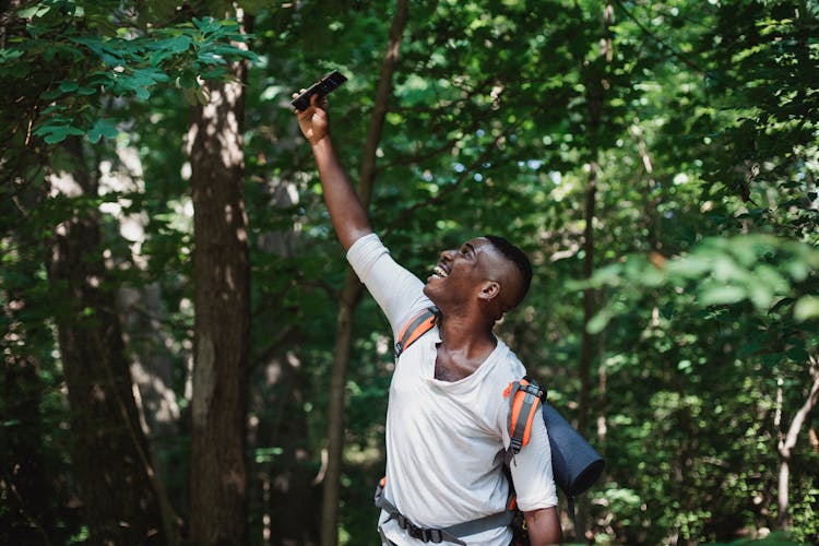 Cheerful Black Man Having Signal On Smartphone In Forest